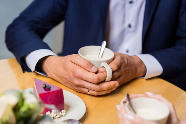 man drinks coffee with fruit cakes at a cafe