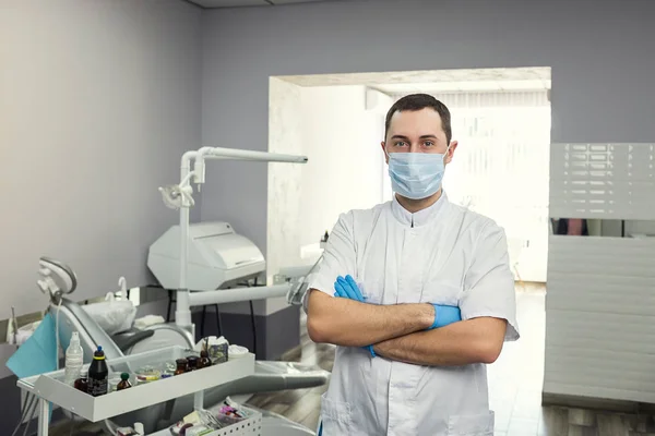 Mannelijke tandarts permanent met zijn handen gekruist over medische kantoor achtergrond. Gezondheidszorg, beroep, Stomatologie en geneeskunde concept — Stockfoto