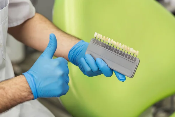 Male dentist with tools over medical office background. Healthcare, profession, stomatology and medicine concept