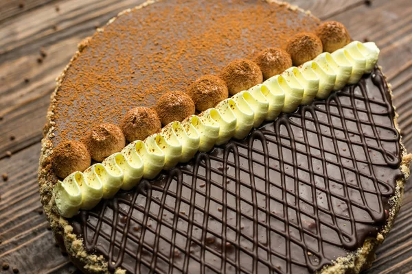 Veganer Kuchen aus dunkler Schokolade mit Bonbons und Nüssen auf Holzbackgr — Stockfoto