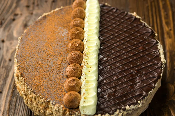 Gâteau végétalien au chocolat noir avec des bonbons et des noix sur backgr en bois — Photo