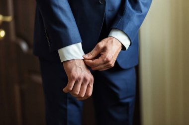 İş adamı ceket giyiyor, erkek eli kapalı, damat düğün töreninden önce hazırlanıyor.
