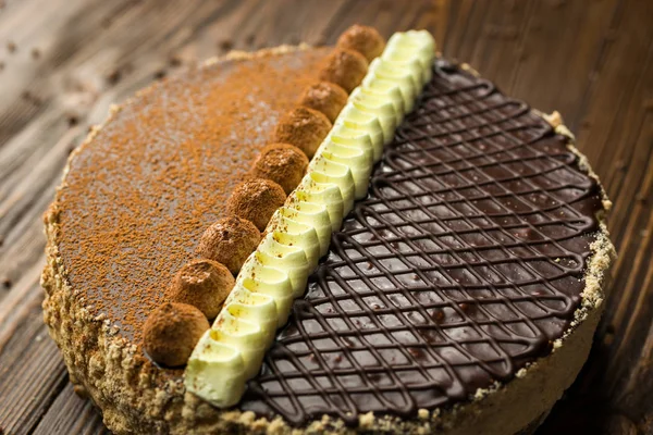 Темный шоколадный веганский торт с конфетами и орехами на деревянном нарте — стоковое фото