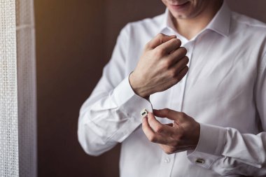 İş adamı beyaz gömlek giyer, erkek eli yakın durur, damat düğün töreninden önce sabah hazırlanır.