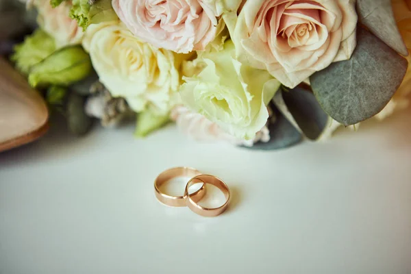 Jegygyűrű feküdjön a tábla közelében egy esküvői csokor — Stock Fotó