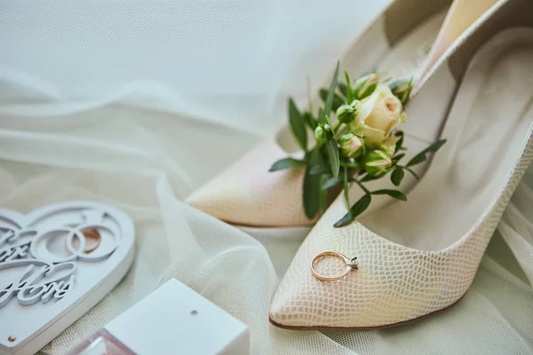 Accessori nuziali come scarpe, bouquet, anello e profumo si trovano su un tavolo Fotografia Stock
