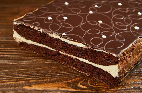 Dark chocolate vegan cake with candies and nuts on wooden background