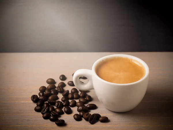 Cup of hot espresso coffee and crop beans on wood background — Stock Photo, Image