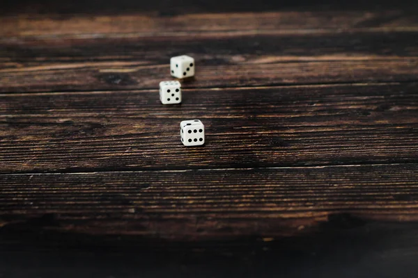 three white dice thrown on a wooden table