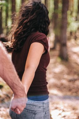 Gün batımında ormanda yürüyen genç bir çift.