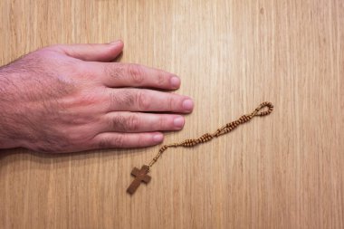 Tahta bir tespihin yanında duran adamın eli.