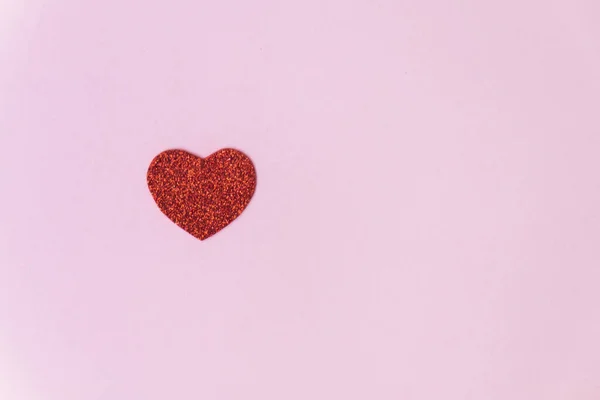 Un corazón rojo brillante y brillante sobre un fondo rosa — Foto de Stock