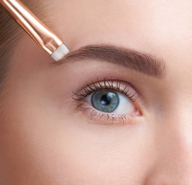 Kaşları bakım. Kadın güzel mavi göz, mükemmel portre profesyonel makyaj ve kaş jel fırçası ile uzun kirpik kaş, şeklinde. Genç kadın modeli kahverengi kaş şekillendirme. Yüksek çözünürlüklü görüntü