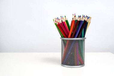 Beyaz masa ve beyaz arka planda gümüş ofis kupasında çeşitli renkli kalemler. - Okul. Çocuklar.