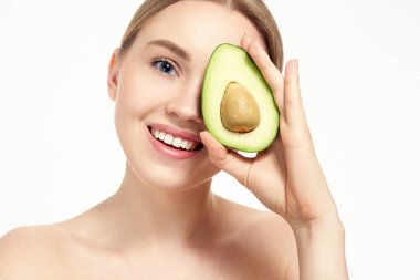 Beyaz stüdyoda avokadoyla çekilmiş, beyaz tenli, gülümseyen sarışın kadının portresi. Pozitif çıplak doğal kadın. Cilt bakımı. Temiz, taze deri. sağlıklı yaşam tarzı.