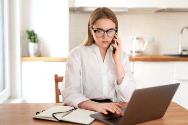 Mutfakta dizüstü bilgisayarda çalışan bir kadın. Telefonla konuşuyorum. İş kadını önemli bir şey düşünüyor. İş arayan bir kadın. Kriz
