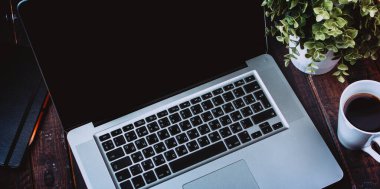 Eski ahşap masada kahve fincanı olan beyaz bir laptop. Evden çalışıyorum. Evden ders çalışmak