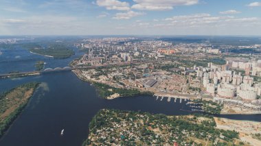Dinyeper Nehri'nin havadan görünümü. Güney Köprüsü. Panorama. Köprüler. Yaz. Güneş. Bir gün. Yeşil ağaçlar. Yüksek binalar. Gökyüzü. Bulutlar. Ada nehir arasında.