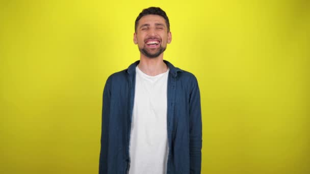 Jovem Camisa Azul Camiseta Branca Olha Para Câmera Fundo Amarelo — Vídeo de Stock