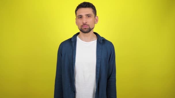 Young Man Blue Shirt White Shirt Looking Camera Yellow Background — Stock Video