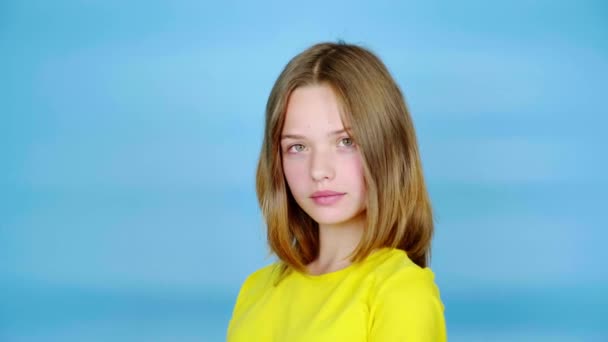 Έφηβη Κίτρινο Μπλουζάκι Ποζάρει Και Κοιτάζει Την Κάμερα Μπλε Φόντο — Αρχείο Βίντεο