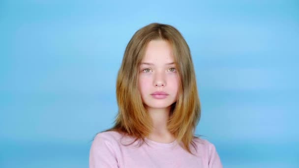 Tonårstjejen Rosa Tröja Poserar Och Tittar Kameran Blå Bakgrund Med — Stockvideo