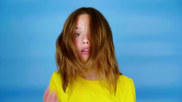 穿着黄色T恤的少女非常吃惊 用手捂住嘴 蓝色背景 有复制空间 青少年的情绪 4K镜头 — 图库视频影像