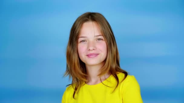 Щаслива Дівчина Підліток Жовтій Футболці Дивиться Камеру Посміхається Синій Фон — стокове відео