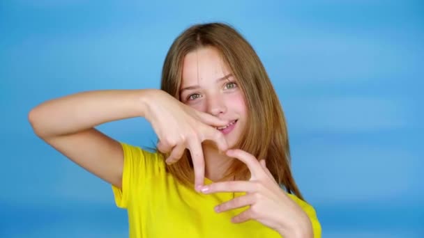 Teen Girl Yellow Shirt Showing Heart Shape Looking Camera Blue — Stock Video