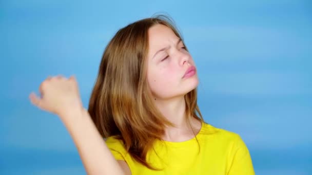 身穿黄色T恤的少女环视四周 想知道该选择什么 蓝色背景 有复制空间 青少年的情绪 4K镜头 — 图库视频影像