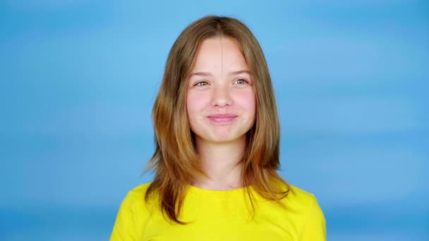 Teen Girl Yellow Shirt Looking Camera Smiles Blue Background Copy — Stock Video