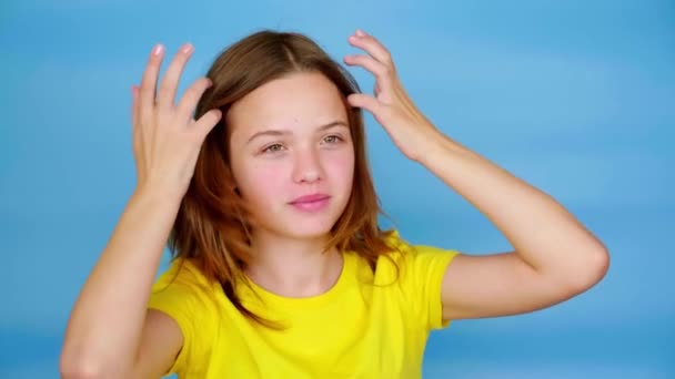 Chica Adolescente Una Camiseta Amarilla Alisar Pelo Sonríe Fondo Azul — Vídeos de Stock