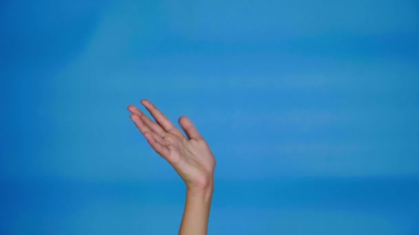女性の手はコピースペースの青い背景の波です 十代の女の子の手 4Kスローモーション映像 — ストック動画