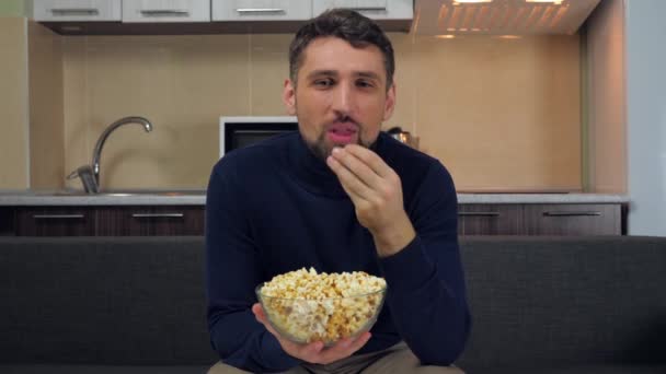 Mladý Muž Tmavomodrém Svetru Šedých Kalhotách Sedí Gauči Popcorn Průhledného — Stock video