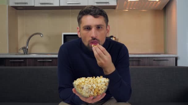 Vážný Mladý Muž Tmavomodrém Svetru Šedých Kalhotách Sedí Gauči Popcorn — Stock video