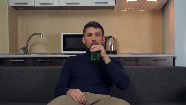 Mladý Muž Tmavomodrém Svetru Šedých Kalhotách Sedí Gauči Pije Pivo — Stock video