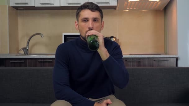 Jovem Pulôver Azul Escuro Calças Cinza Sentado Sofá Bebendo Cerveja — Vídeo de Stock