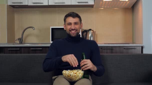 Mladý Muž Tmavomodrém Svetru Šedých Kalhotách Sedí Gauči Popcorn Pije — Stock video