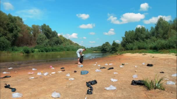 Timelapse of a man who collects plastic trash on the banks of polluted river — 비디오