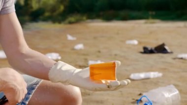 Plastik çöpleri toplayan ve akıllı telefonla analiz yapan bir adamın yakın çekimi..