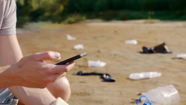 Närbild av en man som plockar upp plast skräp och gör analys med smartphone. — Stockvideo