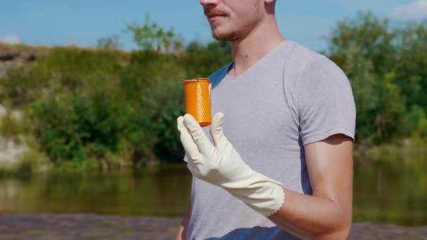 Primo piano di un uomo che tiene la spazzatura di plastica lungo le rive di un fiume secco e inquinato — Video Stock