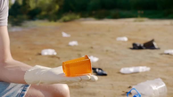 Primer plano de un hombre que recoge basura plástica y hace análisis con un smartphone . — Vídeos de Stock