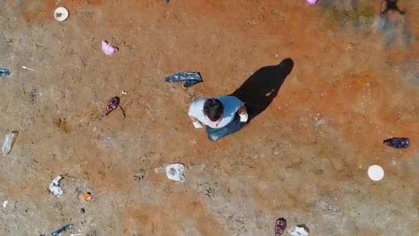 Vista aérea superior del hombre que está parado a lo largo de la basura de plástico en las orillas del río contaminado — Vídeo de stock