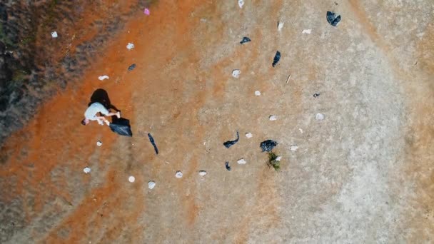 Luftaufnahme von einem Mann, der Plastikmüll am Ufer des verschmutzten Flusses sammelt — Stockvideo