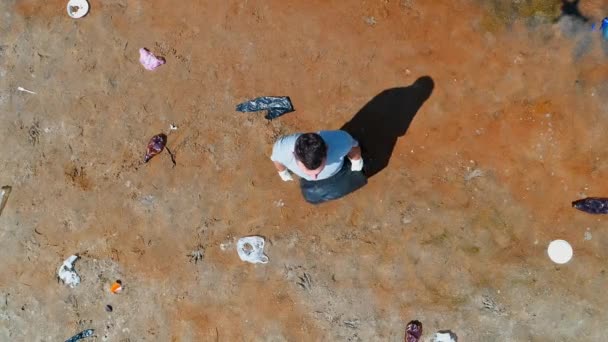 Vue aérienne du dessus de l'homme qui se tient le long des déchets plastiques sur les rives d'une rivière polluée — Video
