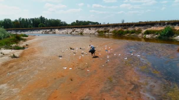 Widok z powietrza człowieka, który zbiera plastikowe śmieci na brzegach zanieczyszczonej rzeki — Wideo stockowe