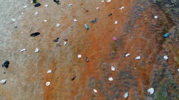 Vista aérea del hombre que está parado a lo largo de la basura de plástico en las orillas del río contaminado — Vídeos de Stock