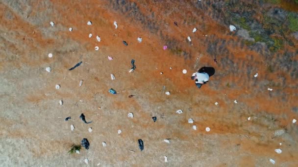 Vue aérienne du dessus de l'homme qui ramasse les déchets plastiques sur les rives d'une rivière polluée — Video