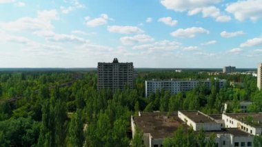 Aerial view of abandoned buildings and streets overgrown with trees in city Pripyat near Chernobyl nuclear power plant. Exclusion Zone. Camera approaching. Sign of USSR on the roof. 4K drone footage.